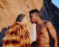 a man and woman kissing in front of a rock