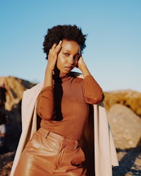 a woman in brown leather pants is posing for a photo