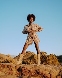 a woman in a dress and boots standing on a rock