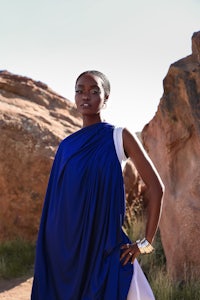 a woman in a blue and white dress posing in front of rocks