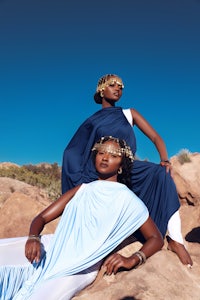 two women in blue dresses posing on a rock